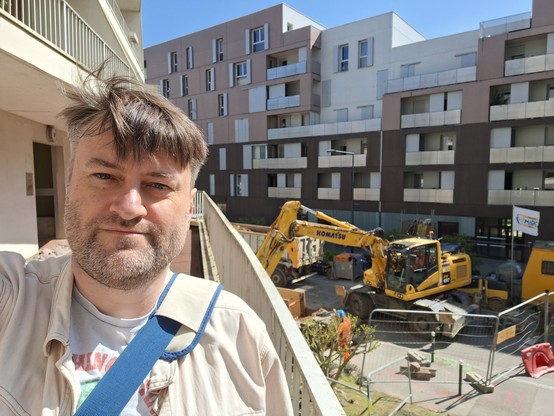 Selfie sur fond de travaux urbains où s'affaire un tractopelle